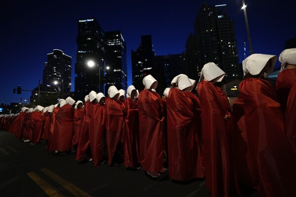 Israeli women's rights activists dressed as characters in the popular television series, "The Handmaid's Tale," protest plans by Prime Minister Benjamin Netanyahu's government to overhaul the judicial system in Tel Aviv, Israel, Saturday, March 11, 2023. (AP Photo/Ohad Zwigenberg)