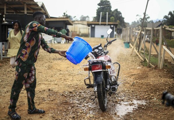 Motorcycle taxi driver Germain Kalubenge pours chlorinated water on his motorcycle after taking a suspected case of Ebola to an Ebola transit center where potential cases are evaluated, in Beni, Congo, Thursday, Aug. 22, 2019. Kalubenge is a rare motorcycle taxi driver who is also an Ebola survivor in eastern Congo, making him a welcome collaborator for health workers who have faced deep community mistrust during the second deadliest Ebola outbreak in history. (AP Photo/Al-hadji Kudra Maliro)