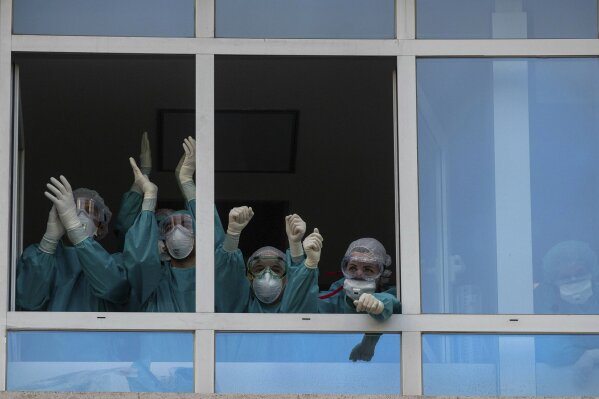 Health workers react as people applaud from their nearby houses in support of the medical staff that are working on the COVID-19 virus outbreak at the Jimenez Diaz Foundation University hospital in Madrid, Spain, Wednesday, April 15, 2020. Spain has eased this week the conditions of Europe's strictest lockdown, allowing manufacturing, construction and other nonessential activity in an attempt to cushion the economic impact of the pandemic. (AP Photo/Manu Fernandez)