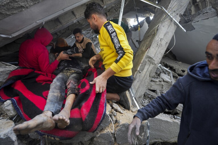 Palestinians pull a body out of the rubble of the Al Nawasrah family building destroyed in an Israeli airstrike in Maghazi refugee camp, central Gaza Strip, Monday, Dec. 25, 2023. (AP Photo/Adel Hana)