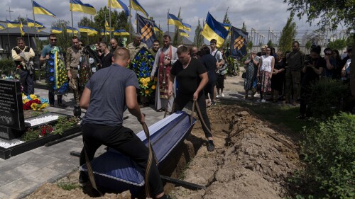 A casket carrying the remains of Roman Shadlovskyi is lowered into the ground during his reburial service in Bucha, Ukraine, Tuesday, July 18, 2023. The Ukrainian Armed Forces veteran, who was initially buried in a mass grave as an unidentified victim after being killed last year by Russian troops, received a reburial Tuesday after a DNA test confirmed his identity. (AP Photo/Jae C. Hong)