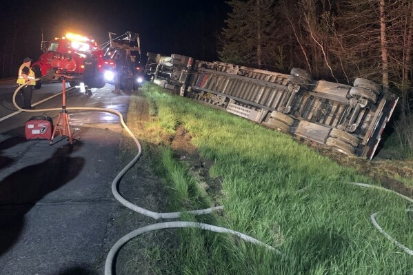 CORRECTS DATE TO MAY 9, NOT MAY 10 - In this image provided by Maine State Police, emergency crews work to remove a tractor-trailer hauling 15 million bees to be used in pollinating the state's blueberry crops after it overturned on Interstate-95, Thursday evening, May 9, 2024, in Clinton, Maine. The driver was taken to a hospital and most of the bees were contained, officials said. (Maine State Police via AP)