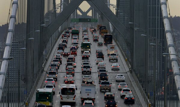 
              FILE - In this Dec. 10, 2015 file photo, vehicles make their way westbound on Interstate 80 across the San Francisco-Oakland Bay Bridge as seen from Treasure Island in San Francisco. As the Trump administration rolls back environmental and safety rules for the U.S. energy sector, government projections show billions of dollars in savings reaped by companies will come at a steep cost: increased premature deaths and illnesses from air pollution, a jump in climate-warming emissions and more derailments of trains carrying explosive fuels. (AP Photo/Ben Margot, File)
            