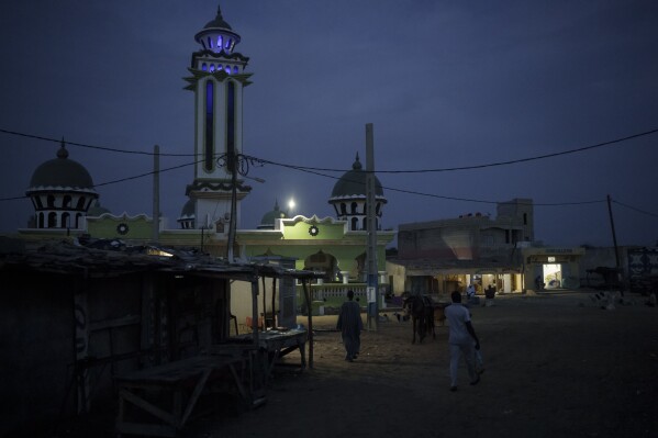 La gente pasa junto a la mezquita de Fass Boye, Senegal, el martes 29 de agosto de 2023. (AP Foto/Felipe Dana)