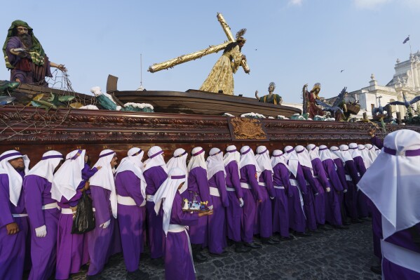 Penitents known as cucuruchos shoulder a religious float with a 300-year-old, life-sized statue of Jesus Christ bearing the cross, during a procession marking the start of Holy Week, in Antigua, Guatemala, on Palm Sunday, March 24, 2024. (AP Photo/Moises Castillo)