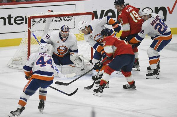 New York Islanders' Ryan Pulock, center, stops the puck in front of Florida Panthers' Sam Reinhart during the first period of an NHL hockey game, Sunday, Oct. 23, 2022, in Sunrise, Fla. (AP Photo/Michael Laughlin)