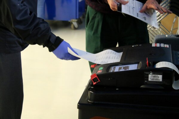 In this Saturday, March 14, 2020 photo, voters cast their ballots during early voting in Chicago while wearing protective gloves. Residents and poll workers took extra precautions amid concerns over the coronavirus. The Illinois state primary elections are scheduled for Tuesday, March 17.  (AP Photo/Noreen Nasir)