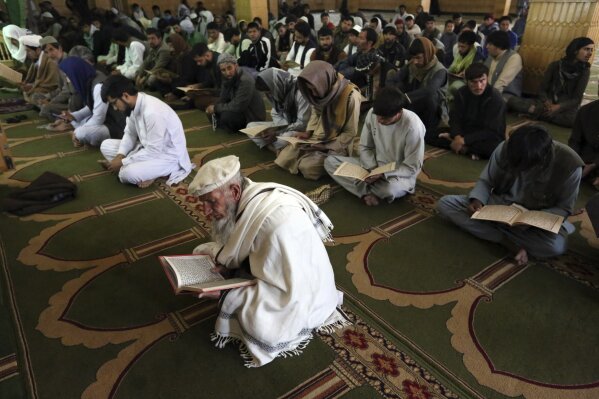 Muslim men read the Quran during the first day of the holy fasting month of Ramadan at a mosque in Kabul, Afghanistan, Friday, April 24, 2020. Millions of Muslims have started the holiest month on the Islamic calendar under the coronavirus lockdown or strict social restrictions, deepening their anxiety over the disease. (AP Photo/Rahmat Gul)