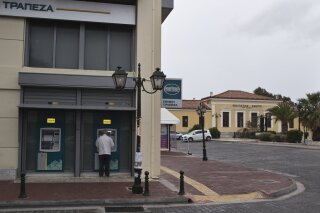 
              A man uses an ATM of a bank in the port town of Lavrio, Greece, about 75 kilometers (48miles) south of Athens, on Thursday, Sept. 27, 2018.  Greek authorities say they will soon lift restrictions on domestic cash withdrawals imposed more than three-years ago to prevent a bank run by depositors at the height of the country's debt crisis. (AP Photo/Petros Giannakouris)
            