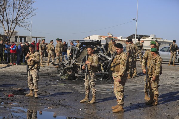 Lebanese army soldiers gather near a charred car that was hit by an Israeli strike, in the southern coastal town of Ghazieh, Lebanon, Friday, April 18, 2025. (AP Photo/Mohammed Zaatari)