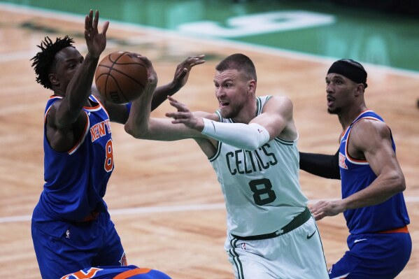 Boston Celtics center Kristaps Porzingis (8) passes the ball while pressured by the New York Knicks during the first half of Game 1 of an NBA basketball second-round playoff series Monday, May 5, 2025, in Boston. (AP Photo/Charles Krupa)