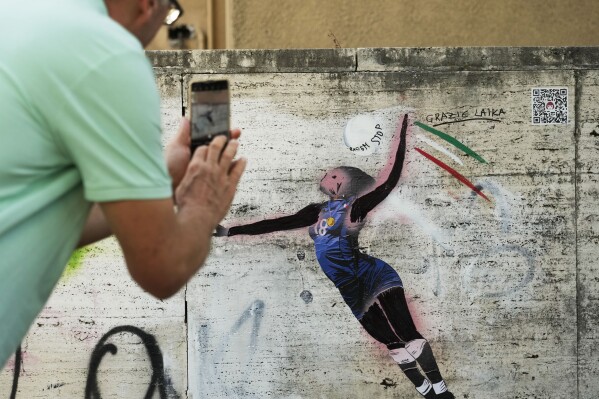 A man takes a picture at Laika's street-art celebration of Paola Egonu, who helped lead Italy to its first-ever Olympic gold medal in women's volleyball, in Rome, Wednesday, Aug. 14, 2024. (AP Photo/Gregorio Borgia)