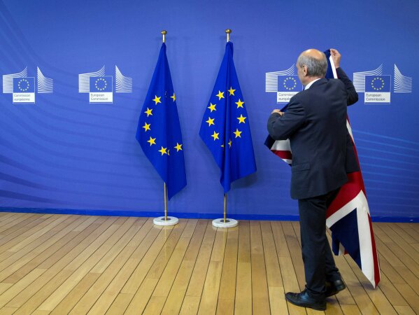 
              FILE - In this June 19, 2017 file photo, a member of protocol changes the EU and British flags at EU headquarters in Brussels. British lawmakers on Tuesday, Jan. 15, 2019 overwhelmingly rejected Prime Minister Theresa May's divorce deal with the European Union, plunging the Brexit process into chaos. (AP Photo/Virginia Mayo, File)
            