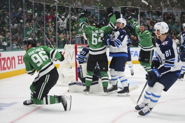Dallas Stars' Mikko Rantanen (96), Mikael Granlund (64) and Roope Hintz, rear, celebrate Rantanen's goal as Winnipeg Jets' Neal Pionk (4) and Kyle Connor (81) look on in the third period of Game 3 of a second-round NHL hockey playoff series in Dallas, Sunday, May 11, 2025. (AP Photo/Julio Cortez)