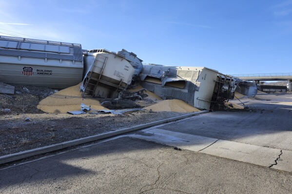 This photo provided by the Elko, Nev., Police Department shows some of 16 grain hoppers of a Union Pacific freight train that derailed early Wednesday, Feb. 28, 2024, spilling a cargo of corn beneath a key railroad overpass in northeast Nevada. No injuries were reported and no hazardous materials were involved, but eastbound and westbound rail service was suspended on the Union Pacific line; the tracks also serve Amtrak service between Chicago and the San Francisco Bay area. (Rick Moore/Elko Police Department via AP)