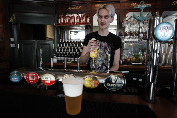 A barman pours a beer at the Crabtree Pub in London, Tuesday, June 23, 2020. Millions of people in Britain will be able to go to the pub, visit a movie theater, get a haircut or attend a religious service starting July 4, in a major loosening of coronavirus lockdown restrictions. The government also announced that from July 4 people will be advised to stay at least 1 meter (3 feet) apart, rather than 2 meters -- as long as they take other measures to reduce transmission of the virus, such as wearing a mask in enclosed spaces. (AP Photo/Frank Augstein)