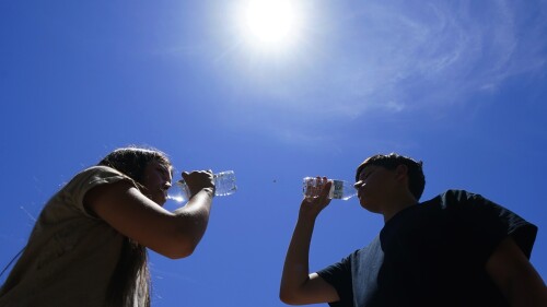 Tony Berastegui Jr., 15, right, and his sister Giselle Berastegui, 12, drink water as temperatures are expected to hit 115-degrees, Monday, July 17, 2023, in Phoenix. (AP Photo/Ross D. Franklin)