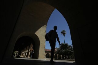 FILE - In this April 9, 2019, file photo, pedestrians walk on the campus at Stanford University in Stanford, Calif. The Education Department released a report Tuesday, Oct. 20, 2020, amid its effort to enforce a 1986 law requiring U.S. universities to disclose gifts and contracts from foreign sources. The department’s findings are primarily based on investigations it has opened at 12 schools, including Harvard, Yale, Stanford and Georgetown universities. (AP Photo/Jeff Chiu, File)
