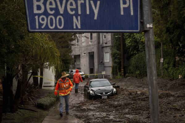 Workers survey a mudslide Tuesday, Feb. 6, 2024, in the Beverly Crest area of Los Angeles. (AP Photo/Ethan Swope)