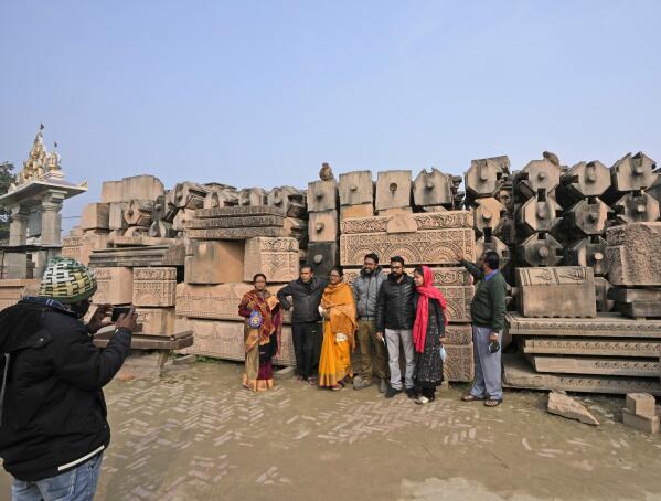 Hindu devotees get their photographs clicked in front of the bricks and blocks which are expected to be used in constructing Ram temple, demanded by millions of Hindus for over 100 years, in Ayodhya, in the Indian state of Uttar Pradesh, Feb. 3, 2022. It's one of several frenetic constructions underway in Ayodhya, where Prime Minister Narendra Modi's Bharatiya Janata Party is seeking reelection by touting Hindu-first politics coupled with economic prosperity. Over 150 million people are expected to vote in the state across seven phases starting Thursday before results are declared in March. (AP Photo/Rajesh Kumar Singh)