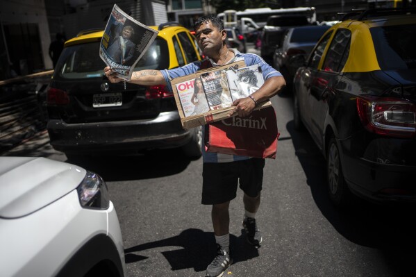 A street vendor sells newspapers featuring the previous day's inauguration of Argentine President Javier Milei in Buenos Aires, Argentina, Monday, Dec. 11, 2023. In his address, Milei presented figures to lay bare the scope of the nation's economic “emergency,” and sought to prepare the public for a shock adjustment with drastic public spending cuts. (AP Photo/Rodrigo Abd)