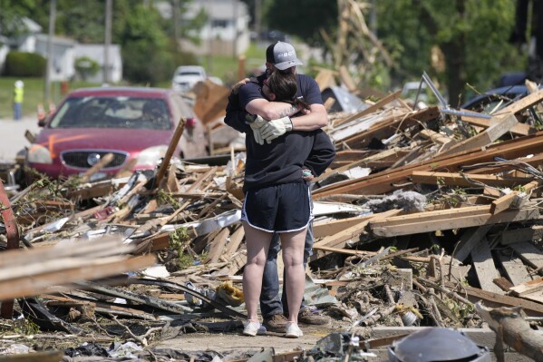 Local residents hug in front of their tornado damaged home, Wednesday, May 22, 2024, in Greenfield, Iowa. (AP Photo/Charlie Neibergall)