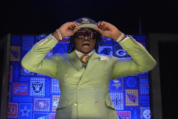 Alabama linebacker Dallas Turner reacts as he puts on a hat after being chosen by the Minnesota Vikings with the 17th overall pick during the first round of the NFL football draft, Thursday, April 25, 2024, in Detroit. (AP Photo/Jeff Roberson)