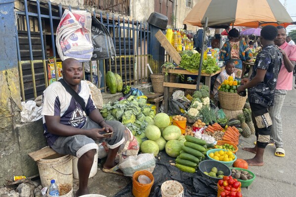 A man sells fruits at a market in Lagos, Nigeria Wednesday , Nov 29, 2023. Nigeria's leader on Wednesday presented a $34 billion spending plan for 2024 to federal lawmakers with a key focus on stabilizing Africa's largest but ailing economy and fighting the nation's deadly security crisis. (AP Photo/Sunday Alamba)