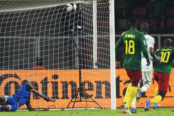 Comoros' goalkeeper Chaker Alhadhur, left, fails to stop a goal shot from Cameroon's Vincent Aboubakar, far right, during the African Cup of Nations 2022 round of 16 soccer match between Cameroon and Comoros at the Olembe stadium in Yaounde, Cameroon, Monday, Jan. 24, 2022. (AP Photo/Themba Hadebe)