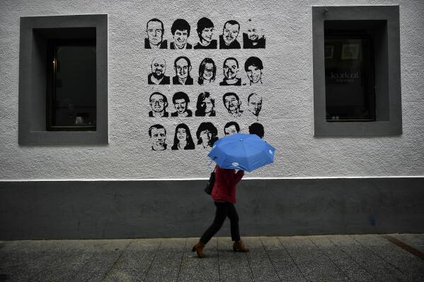 A woman shelters from the rain under an umbrella, while walking past a wall painted with portraits of prisoners of the Basque separatist armed group ETA, in the small village of Hernani, northern Spain, May 2, 2018. The United States is poised to remove five extremist groups, all believed to be defunct, from its list of foreign terrorist organizations. Several of these groups once posed significant threats, killing hundreds if not thousands of people across Asia, Europe and the Middle East. The organizations include the Basque separatist group ETA , the Japanese cult Aum Shinrikyo, the radical Jewish group Kahane Kach and two Islamic groups that have been active in Israel, the Palestinian territories and Egypt. (Alvaro Barrientos, file)