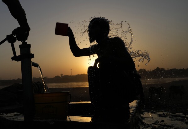 DOSSIER - Un jeune Pakistanais se rafraîchit sous une pompe manuelle au coucher du soleil par temps chaud à Lahore, au Pakistan, le 28 mai 2024. Mois après mois, les températures mondiales établissent de nouveaux records.  (Photo AP/KM Chaudary, dossier)