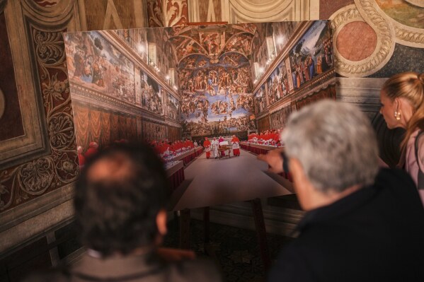 Journalists look at a photograph of the conclave where late Pope Francis was elected on March 13, 2013, and displayed inside the Borgia Apartments at the Vatican Museums during a press tour, Friday, May 2, 2025. (AP Photo/Francisco Seco)