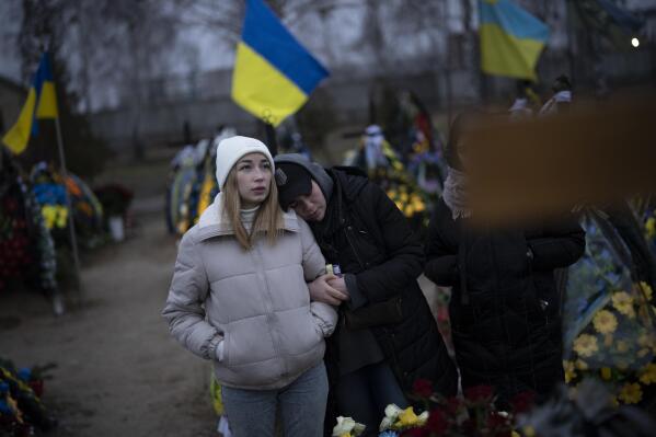 Anastasiia Okhrimenko, left, and Anna Korostenska visit the cemetery together in Bucha, Ukraine, where their partners are buried, Monday, Jan. 23, 2023. As the conflict that killed their loved ones still rages on, Anna, Anastasiia and her brother, Vadym wrestle with a question that all of war-torn Ukraine must grapple with: After loss, what comes next? (AP Photo/Daniel Cole)