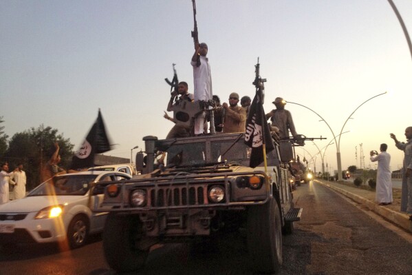 FILE - fighters from the Islamic State group parade in a commandeered Iraqi security forces armored vehicle in the northern city of Mosul, Iraq, June 23, 2014. The Islamic State group announced Thursday the death of its little known leader Abu al-Hussein al-Husseini al-Qurayshi who had been heading the extremist organization since November. (AP Photo, File)