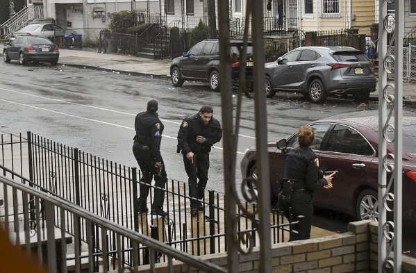 In this Dec. 10, 2019 photo, Jersey City police Sgt. Marjorie Jordan, left, helps fellow officer Raymond Sanchez to safety after he was shot during a gunfight that left multiple dead in Jersey City, N.J. The two killers were armed with a variety of weapons, including an AR-15-style rifle and a shotgun that they were wielding when they stormed into a store in an attack that left the scene littered with several hundred shell casings, broken glass and a community in mourning. Despite years of New Jersey officials focusing on the problems of crime guns coming into the state, Tuesday's shooting shows efforts are falling short. (Justin Moreau via AP)