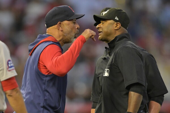 Boston Red Sox manager Alex Cora, left, argues with umpire Alan Porter, front right, as umpire Jim Wolf, back right, looks on after he was ejected in the fifth inning during a baseball game against the Los Angeles Angels, Monday, June 23, 2025, in Anaheim, Calif. (AP Photo/Jayne Kamin-Oncea)
