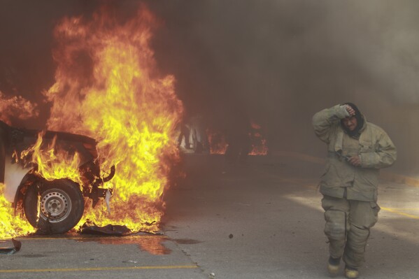A truck burns after it was set fire by rural teachers' college students protesting the previous month's shooting of one of their classmates during a confrontation with police, as firefighters work to control the blazes outside the municipal government palace in Chilpancingo, Mexico, Monday, April 8, 2024. (AP Photo/Alejandrino Gonzalez)