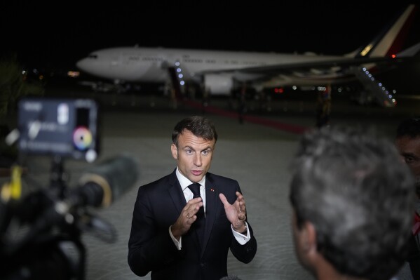 French President Emmanuel Macron talks to journalists on the tarmac of Cairo airport, Egypt, as he departs Wednesday, Oct. 25, 2023. French President Emmanuel Macron sought to promote, yet with little success, the prospect of creating an "international coalition" to fight against the armed Palestinian militant group Hamas, during a two-day trip to the Middle East that started in Israel. (AP Photo/Christophe Ena, Pool)