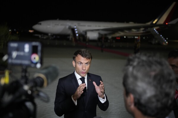 French President Emmanuel Macron talks to journalists on the tarmac of Cairo airport, Egypt, as he departs Wednesday, Oct. 25, 2023. French President Emmanuel Macron sought to promote, yet with little success, the prospect of creating an 