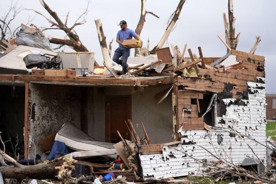 A man sorts through the remains of a home damaged by a tornado Tuesday, May 21, 2024, in Greenfield, Iowa. (AP Photo/Charlie Neibergall)
