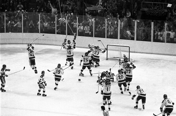 FILE - In this Feb. 22, 1980, file photo, the U.S. ice hockey team rushes toward goalie Jim Craig after their 4-3 upset win over the Soviet Union in a medal round match at the Winter Olympics in Lake Placid, N.Y. Some of the U.S. players shown are Mark Johnson (10); Eric Strobel (19); William Schneider (25); David Christian (23); Mark Wells (15); Steve Cristoff (11); Bob Suter (20) and  Philip Verchota (27).  (AP Photo/File)