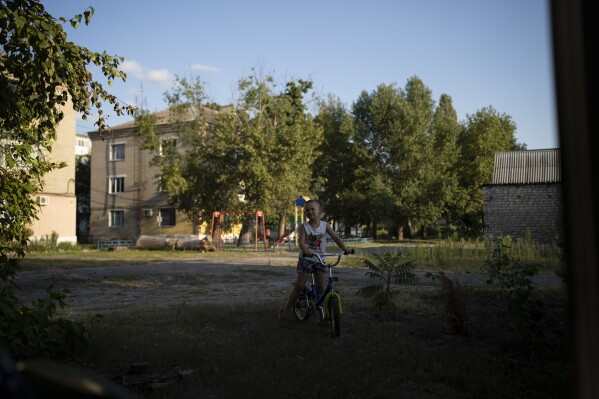 David, 5, stands with his bicycle outside his home in Kupiansk-Vuzlovyi, Ukraine, Wednesday, Aug. 23, 2023. (AP Photo/Bram Janssen)