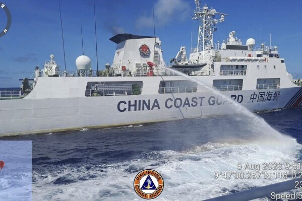 FILE - In this handout photo provided by the Philippine Coast Guard, a Chinese coast guard ship uses water canons on a Philippine Coast Guard ship near the Philippine-occupied Second Thomas Shoal, South China Sea as they blocked it's path during a re-supply mission on Aug. 5, 2023. The Philippine military chief demanded Wednesday that China returns several rifles and equipment seized by the Chinese coast guard in a disputed shoal and pay for damage it caused to two navy rubber boats in an assault he likened to an act of piracy in the South China Sea.. (Philippine Coast Guard via AP)