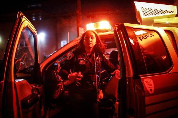 FDNY paramedic Elizabeth Bonilla sprays herself with disinfectant after responding to an emergency call during the coronavirus outbreak Wednesday, April 15, 2020, in the Bronx borough of New York. "Emotionally, you have to be strong for the families that are going through it," she said. "You don't want to cry in front of them. You want to show them that you're strong and you're there to support them." (AP Photo/John Minchillo)