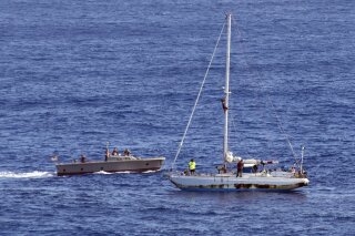 CORRECTS NAME TO TASHA FUIAVA-In this Wednesday, Oct. 25, 2017 photo, sailors from the USS Ashland approach a sailboat with two Honolulu women and their dogs aboard as they are rescued after being lost at sea for several months while trying to sail from Hawaii to Tahiti. The U.S. Navy rescued the women on Wednesday after a Taiwanese fishing vessel spotted them about 900 miles southeast of Japan on Tuesday and alerted the U.S. Coast Guard. The women, identified by the Navy as Jennifer Appel and Tasha Fuiava, lost their engine in bad weather in late May, but believed they could still reach Tahiti. (Mass Communication Specialist 3rd Class Jonathan Clay/U.S. Navy via AP)