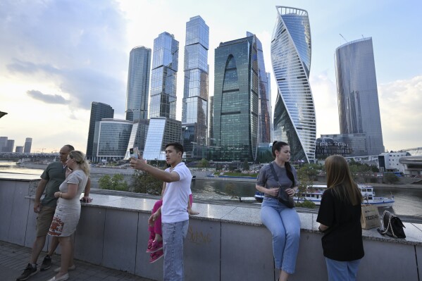 People stroll at embankment of the Moscow River in Moscow, Russia, Tuesday, Aug. 1, 2023, with the "Moscow City" business district in the background. The glittering towers of the Moscow City business district were once symbols of the Russian capital's economic boom in the early 2000s. Now they are a sign of its vulnerability, following a series of drone attacks that rattled some Muscovites shaken and brought the war in Ukraine home to the seat of Russian power. (AP Photo/Dmitry Serebryakov)