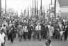 Dr. Martin Luther King, fourth from right, waves as marchers stream across the Alabama River on the first of a five day, 50 mile march to the state capitol at Montgomery, Ala., on March 21, 1965. (AP Photo)