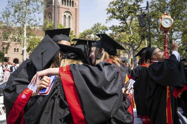 File - Graduates embrace during Southern California's 140th commencement ceremony, on May 12, 2023, in Los Angeles. Interest on federal student loans has started accumulating again after a three-year pause because of the COVID-19 pandemic. Borrowers still have another month before they'll need to start paying back loans. (Sarah Reingewirtz/The Orange County Register via AP, File)