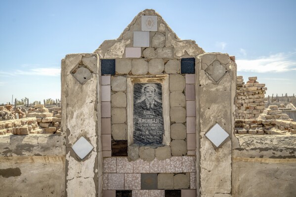 A man's photo is placed on his grave in a cemetery near the dried-up Aral Sea, on the outskirts of Muynak, Uzbekistan, Monday, June 26, 2023. (AP Photo/Ebrahim Noroozi)