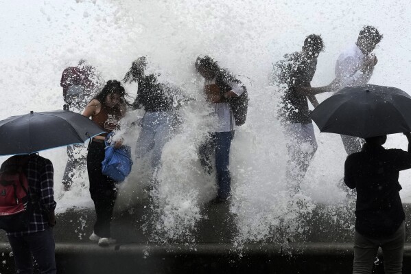 People enjoy high tide waves on the Arabian Sea coast in Mumbai, India, Thursday, July 6, 2023.(AP Photo/Rajanish Kakade)